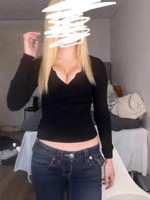 Svart v-ringad långärmad topp - Svart långärmad topp med v-ringning och figurnära passform. Toppen har en enkel och stilren design som framhäver siluetten. Perfekt att matcha med jeans eller kjol för en trendig look.