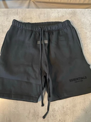 Svarta fear of god essentials mjukisshorts storlek M - Fear of God Essentials mjukisshorts i svart, storlek M. Endast provade och därför i nyskick.  Bekväma shorts med avslappnad passform, perfekta till vardags. Hör gärna av dig om du har några frågor eller vill se fler bilder.