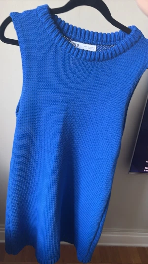Blå stickad ärmlös klänning Zara - Säljer en blå stickad klänning från Zara. Klänningen är ärmlös med rund halsringning och har en enkel, rak passform. 