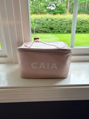 Ljusrosa necessär från CAIA - Säljer en ljusrosa necessär från CAIA med vit logga på framsidan. Den är ganska stor i storleken. Perfekt att ha som prydnad, går att använda men sminkfläckar på insidan finns, även andra smådefekter om man kollar nära. Använt skick men fortfarande fin och brukbar. Skriv gärna om intresserad, Mvh Julia