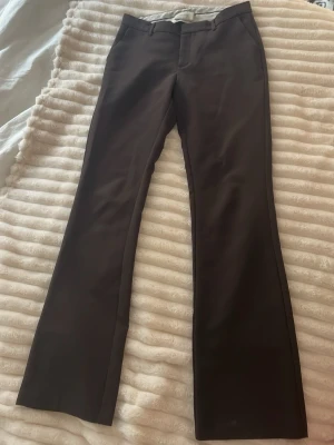 Bruna kostymbyxor från Neo Noir - Snygga bruna kostymbyxor från Neo Noir med veck. Storlek 36! Perfekt passform och lågmidjade, bra längd som täcker en bit av skorna. Säljs pga blivit för korta