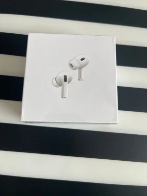 Apple AirPods Pro (2nd Gen) USB-C - Säljer ett par vita Apple AirPods Pro (2nd generation) med MagSafe-laddningsetui och USB-C. Trådlösa in-ear hörlurar med stilren design och brusreducering. Perfekta för musik, samtal och gaming. Levereras i originalförpackning.