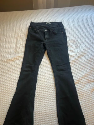 Svarta bootcut jeans - Säljer ett par svarta bootcut jeans. Jeansen har utsvängda ben och är lågmidjade. Byxorna är lite söndertrampade efter användning. Säljer för att de var smått för långa och stora för mig. Passar de som är 165 och längre.