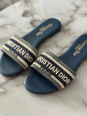 Mörkblå sandaler  - . Klassisk slip-in modell med platt sula och exklusiv känsla. Perfekta för en trendig och avslappnad look.