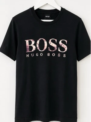 Svart Hugo Boss t-shirt med logga (Äkta) - (Äkta) Snygg svart t-shirt från Hugo Boss med stor BOSS-logga i vitt och rosa på bröstet. Klassisk rund halsringning och korta ärmar. Tillverkad i mjukt bomullsmaterial som känns skönt mot huden. Perfekt för en stilren och avslappnad look.