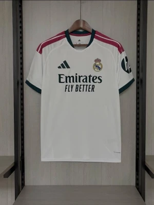 Real Madrid matchtröja Adidas - Snygg vit Real Madrid matchtröja från Adidas med gröna detaljer och vinröda ränder på axlarna. Tröjan har klubbmärke, Adidas-logga och sponsortryck på bröstet samt HP-logga på ärmen. Tillverkad i lätt och ventilerande material, perfekt för fotbollsträning eller match.