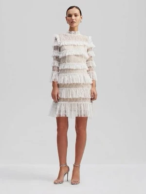 Vit kortklänning med volanger - Trendig vit kortklänning med volangdetaljer och hög hals. Klänningen har långärmade ärmar i transparent spets och flera lager med fransar som ger en cool och lekfull look. Perfekt för dig som vill sticka ut med en unik stil. Använd endast en gång.