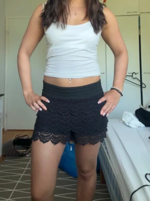 Svarta virkade shorts med volang - Snygga svarta shorts med spets. De har en feminin look med detaljerad spetskant och sitter skönt på höften. Perfekta för varma dagar och ger en chill men ändå stilsäker vibe. Storlek 34, passar xs-s. 🤍