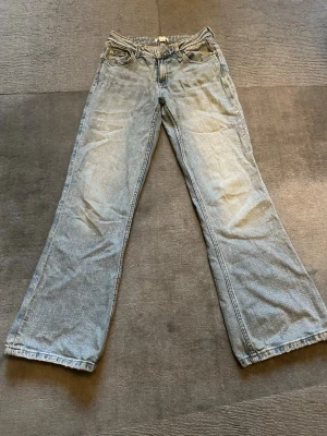 Lågmidjade bootcut jeans - Säljer ett par ljusblå lågmidjade jeans från Gina tricot. Dom har släppt lite i tyget där fram och lite där bak. Perfekta för en avslappnad stil. Storlek 152