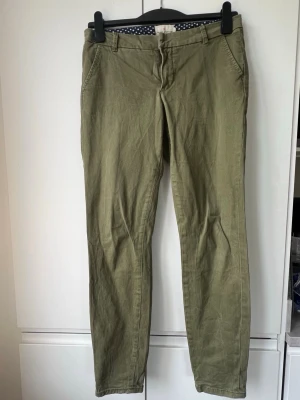 Olivgröna chinos från Holly & Whyte - Snygga olivgröna chinos från Holly & Whyte by Lindex. Klassisk rak passform med fickor fram och bak, bälteshällor och dragkedjegylf. 