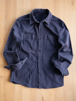 Grå overshirt i bomull - Stilren grå overshirt med två bröstfickor och knappar framtill. Skjortan är tillverkad i mjuk bomull och har klassisk krage samt långa ärmar. Perfekt att bära öppen eller stängd för en avslappnad look.