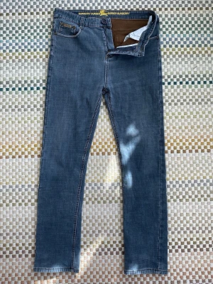 Blå jeans från Burberry - Snygga blå jeans från Burberry med smal passform och klassisk femficksdesign. Jeansen har diskreta kontrastsömmar och Burberry-logga på bakfickan. Tillverkade i mjukt denimtyg som ger en bekväm känsla och stilren look. Storlek 34.