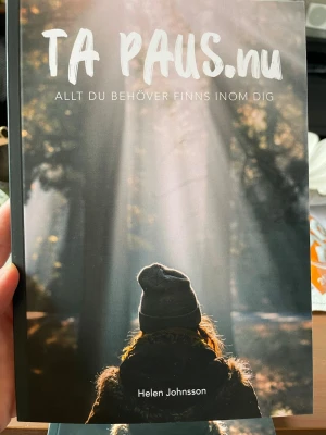 Ta Paus.nu av Helen Johnsson - En inspirerande bok med mjukt omslag, skriven av Helen Johnsson. Boken handlar om att hitta balans i livet, ta pauser och leva mer närvarande. Omslaget har en bild på en person i naturen med solstrålar som lyser genom träden. Perfekt för dig som vill reflektera och utvecklas. En självhjälpsbok med personlig utveckling för dig som är på väg att bränna ut dig, har bränt ut dig eller behöver lära dig mer om läkning inuti