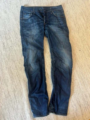 Mörkblå jeans med tvättade detaljer - Säljer ett par mörkblå jeans med snygga tvättade detaljer och kontrastsömmar. Storlek: waist 29, length 32.