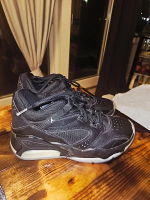 Svarta Air Jordan sneakers - Säljer ett par svarta Air Jordan sneakers med högt skaft. Skorna har en mix av läder och mesh, samt den klassiska Jumpman-loggan på plösen. Sulan är tjock och har en synlig luftbubbla på sidan för extra komfort. Snygga detaljer och sportig look.