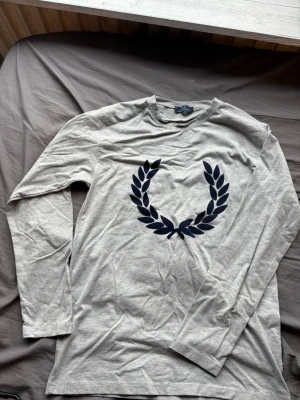 Grå långärmad t-shirt Fred Perry - Fred perry tröja, stilren och funkar till skolan. Använder ej längre därför säljs den. Passar M och S kan funka på en Large person som är lite smalare.