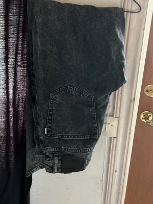 Woodbird mörkgrå loose fit jeans - Säljer ett par mörkgrå loose fit jeans från Woodbird, modell Lergy Thun Black Jeans. Jeansen har en avslappnad passform, klassiska bakfickor och är tillverkade i tvättad denim. Perfekta för en casual och trendig look.