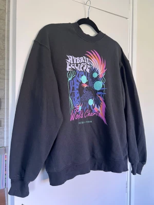 Sweatshirt med färgglatt tryck - mörkgrå/svart sweatshirt sweatshirt från H&M i storlek xxs (oversized, så är mer som en S ungefär!)  använd en handfull gånger. granska bilderna noga!