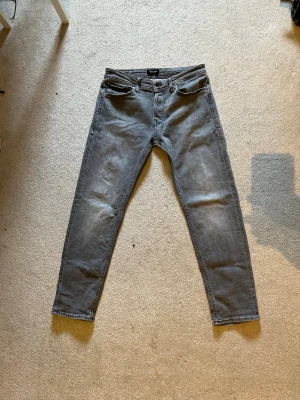 Grå regular fit jeans från Jack & Jones - Säljer ett par grå slim fit jeans från Jack & Jones med klassisk femficksdesign och knappgylf. Jeansen har en snygg tvättad look och raka ben. Perfekta för en avslappnad och trendig stil. Nypris 1000kr Storlek W32 L32