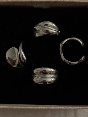 Set med fyra  silverringar - Säljer ett set med fyra coola  ringar i silverfärgad metall. Ringarna har olika former och unika, organiska designer som ger en trendig och modern känsla. Alla går in i priset 