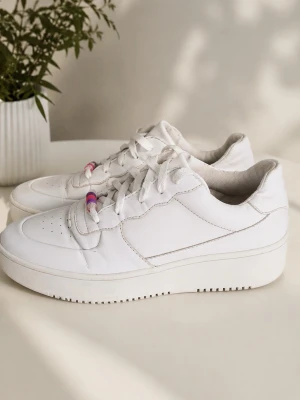 Vita chunky sneakers med pärldetalj - Stilrena vita sneakers med chunky sula och klassisk låg profil. Skorna har vita snören och en unik detalj med färgglada pärlor på ena skon. Tillverkade i syntetmaterial med perforering vid tårna för extra ventilation. Perfekta för en clean och modern look.