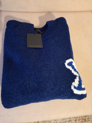 Stickade tröjor med LV-logga – Helt nya (Strl M) - Säljer två helt nya och oanvända grovstickade tröjor i storlek M. Modellerna är helt likadana, det är bara färgen som skiljer dem åt. De har den vita loggan på bröstet och en spegelvänd logga på ryggen.  Storlek: M på båda två.  Färger Mörkblå med vit loggaMörkgrå/Antracit med vit logga Priset är 799 kr per styck.