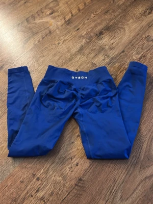 Blå seamless leggings från GTECH - Säljer ett par blå seamless leggings från GTECH med hög midja och stretchigt material. Perfekta för träning eller chill. Tight passform och mjukt tyg som sitter skönt mot kroppen. Diskret logga i midjan och långa ben. Använd fåtal gånger