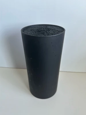 Svart knivställ med borst-insats - Svart knivställ med en flexibel borstinsats som håller knivarna på plats. Stället är 22 cm högt och har en diameter på 11 cm. Insats och ställ i robust plast, går att dela på om man vill stoppa in i diskmaskinen. Smidigt och praktiskt ställ för att hålla ordning i köket. 