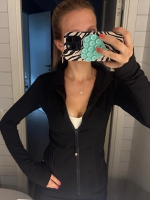Svart träningsjacka från Lululemon - så så snygg Lululemon jacka i svart, är en gammal modell! Storleken är antigen 2 eller 4 men lapp är bortklippt. Skicket är bra men lite nopprig längst ut vid armarna, se sista bild! 