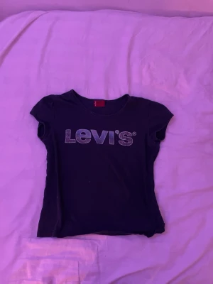 Svart Levi's t-shirt med logga - Svart t-shirt från Levi's med klassisk logga i vitt på bröstet. Modellen är kortärmad och har en rund halsringning. Perfekt för en avslappnad och stilren look.
