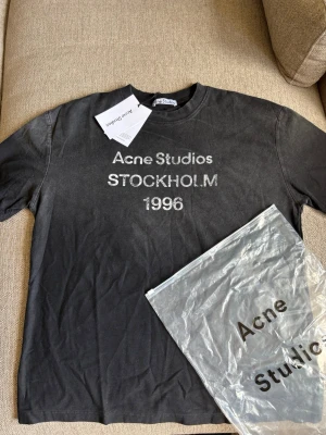 Acne Studios t-shirt - Cool svart t-shirt från Acne Studios med tryck 'Acne Studios STOCKHOLM 1996' på bröstet. KTillverkad i mjuk bomull och levereras med originalpåse och taggar.