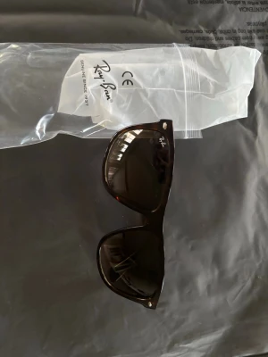 Bruna boyfriend solglasögon från Ray-Ban - Klassiska bruna solglasögon från Ray-Ban med mörka glas och stilren design. Bågarna är i plast och har Ray-Ban-loggan på linsen. Perfekta för dig som vill ha en tidlös och cool look. Helt oanvända 