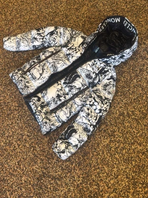 Moncler jacka  - Säljer en riktigt snygg dunjacka från Moncler i svartvitt grafiskt mönster. Jackan har huva med Moncler-logga, två framfickor med dragkedja och klassisk Moncler-patch på ärmen. Perfekt för kalla vinterdagar och riktigt trendig look.