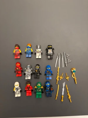 Lego Ninjago figurer och vapen - Säljer ett set med Lego Ninjago minifigurer i olika färger som röd, blå, grön, vit och svart. Medföljer flera tillbehör och vapen i silver och guld, bland annat svärd, spjut och stavar. Perfekt för dig som gillar att bygga och leka med Lego.