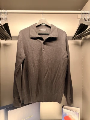 Massimo Dutti - Klassisk svart långärmad tröja från Massimo Dutti med krage och knappslå framtill. Tröjan har en stilren design och är tillverkad i mjukt material som passar perfekt till en avslappnad men ändå snygg look.