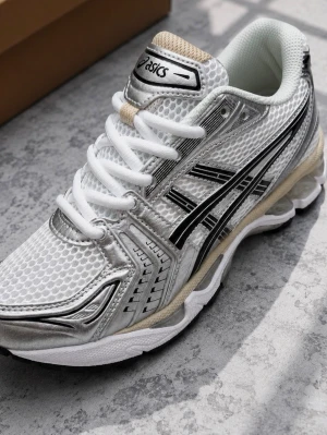 Asics Gel-Kayano 14 silver sneakers - Snygga Asics Gel-Kayano 14 sneakers i silver och vitt med svarta detaljer. Ovandelen är i mesh och syntetmaterial för en sportig vibe. Skorna har vita snören, beige inslag på plösen och en chunky sula med cool design. Perfekta för dig som gillar retrostil och streetwear.
