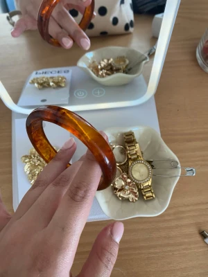 Bärnstensfärgat chunky armband - Snyggt chunky armband i bärnstensfärgad plast med marmorerad effekt. Armbandet har en rund, bred form och ger en cool retrovibe till din outfit. Perfekt för dig som gillar statement-accessoarer och vill sticka ut lite extra.