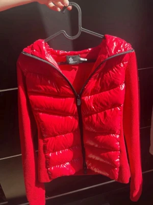 Moncler grenoble röd dunjacka M - INFORMATION: Klarröd, fjäderdun, fodrad design, logotypmärke på ärmen, ärmar i kontrasttyg, klassisk huva, dragkedja i fram. Material: Foder: dunfjädrar 100%, polyamid 100%, polyester 94%, spandex/elastan 6% Yttre: polyamid 100% Tvättinstruktioner: maskintvätt 
