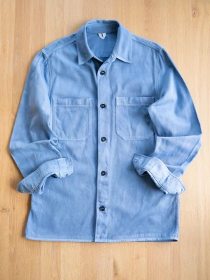 Arket Ljusblå overshirt med fickor - Snygg ljusblå overshirt från Arket i kraftigt bomullstyg med två stora bröstfickor och svarta knappar. Klassisk krage och raka ärmar som kan vikas upp för en avslappnad look. Perfekt att bära över en t-shirt för en trendig lager-på-lager stil.