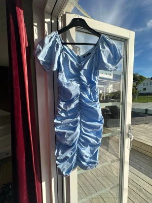 Ljusblå klänning med puffärm. Gina tricot  - Supersöt ljusblå kortklänning från Gina tricot med puffärmar och v-ringning. Klänningen har snygg rynkning längs hela framsidan och baksidan, sitter superfint på. Perfekt för sommarens alla tillfällen! Jättefint skick! 