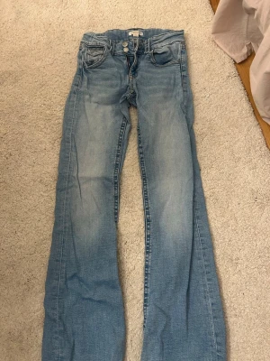 Ljusblå bootcut jeans från Gina Tricot - Säljer ett par ljusblå bootcut jeans från Gina Tricot. Jeansen har klassisk femficksdesign, dubbla knappar i midjan och dragkedja. Tillverkade i mjuk denim med snygg slitning och lätt utsvängda ben. Säljer då jag inte använder dom längre, men är i fint skick! 💞