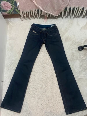 Mörkblå Diesel bootcut jeans f - Säljer ett par lågmidjade mörkblå/marinblå bootcut jeans från diesel med gula stygn. Den är ca 5cm längre ksk mer på mig som är 165. De är mina favorit jeans men tyvärr har jag gott upp i vikt och därav passar de inte längre. Har använt de 2 gånger och de är i helttttt nytt skick 