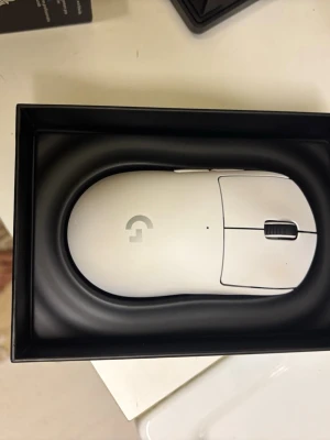  Logitech gaming mus trådlös - Snygg vit trådlös gamingmus från Logitech med stilren design och diskret logotyp på ovansidan. Musen har två huvudknappar, scrollhjul och extra sidoknappar. Perfekt för gaming eller arbete vid datorn.