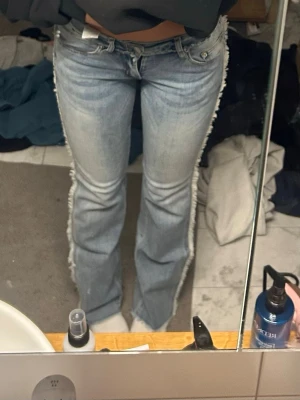Ljusblå bootcut jeans med fransar - Säljer ett par supersnygga ljusblå bootcut jeans från edikted med fransade sidor🥰.