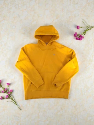Gul hoodie från Tommy Jeans - Snygg gul hoodie från Tommy Jeans med klassisk huva och dragsko. Tillverkad i mjuk bomull och har en liten broderad logga på bröstet. Perfekt för dig som vill sticka ut med färg och samtidigt hålla det stilrent.