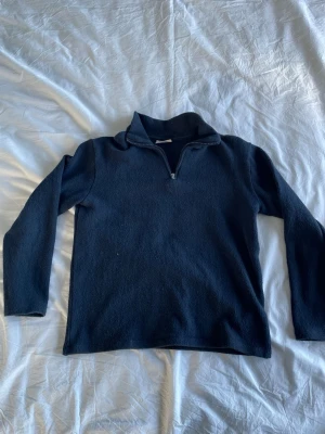 Mörkblå fleece halvzip tröja - Mysig mörkblå fleece tröja med halv dragkedja och hög krage. Perfekt för lager på lager och chill dagar. Enkel och stilren design utan synliga loggor eller mönster. Passar dig som gillar basic och funktionella plagg.