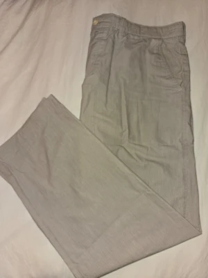 Beige smalrandiga chinos från Hugo Boss - Hugo Boss byxor – Beige (52) Beige byxor från Hugo Boss. Storlek: 52 Skick: Bra begagnat skick.