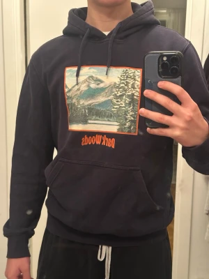 Mörkblå Dark Woods hoodie med tryck - Snygg mörkblå hoodie från Dark Woods med stor färgglad print av berg och skog på bröstet. 