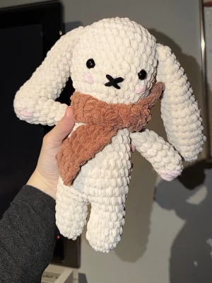 Virkad kanin  - Supergullig handgjord kanin i mjukt, vitt garn med långa öron och svarta ögon. Kaninen har rosa detaljer på kinderna och tassarna samt en virkad brun halsduk runt halsen. 