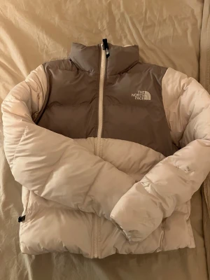 The North Face Saikuru vinterjacka  - Snygg vinterjacka från The North Face i vit och grå/grön☺️ Jackan har hög krage och är supervarm och skön, perfekt för kalla vinterdagar! Som det syns på bilden är det en liten svart fläck på ena ärmen men annars är jackan i väldigt bra skick! Storlek S. Inköpspris 2700kr🤗